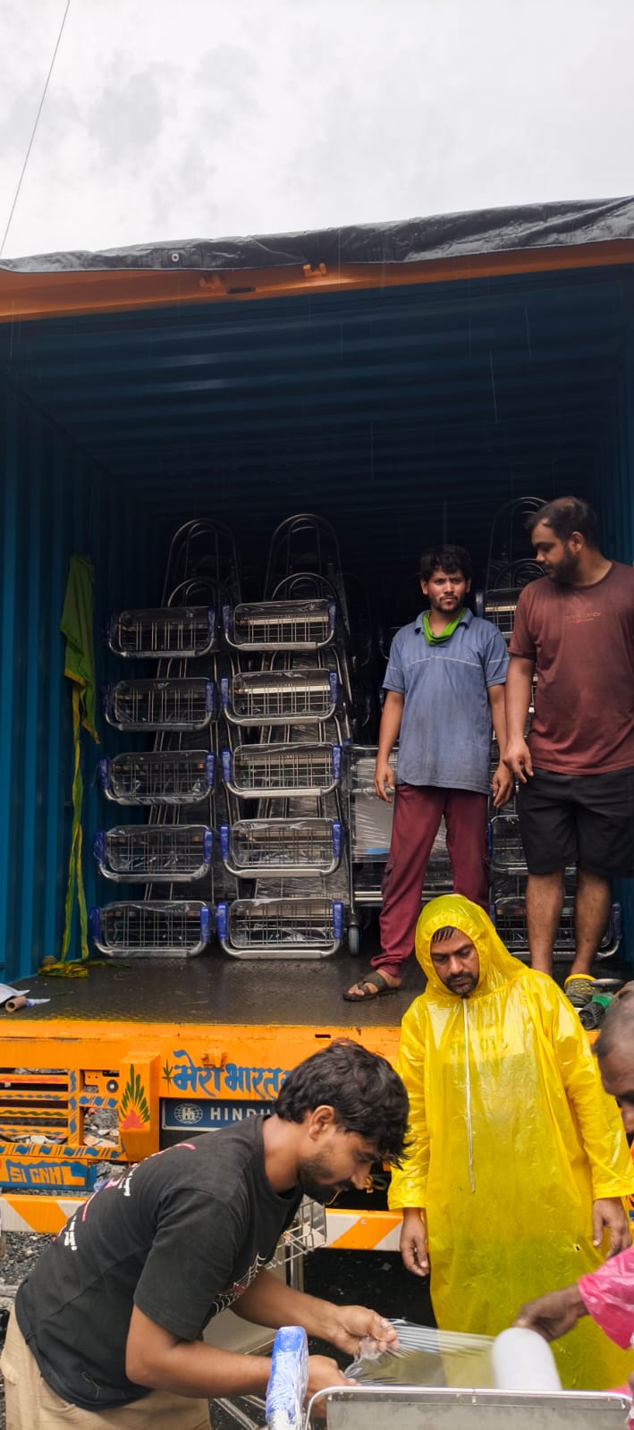 Workers stacking wrapped airport trolleys inside container truck for dispatch